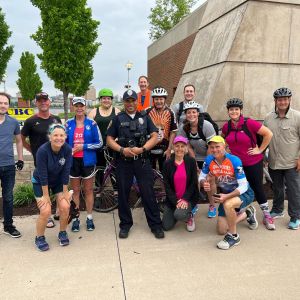 Men and women who ride bicycles standing next to police officer