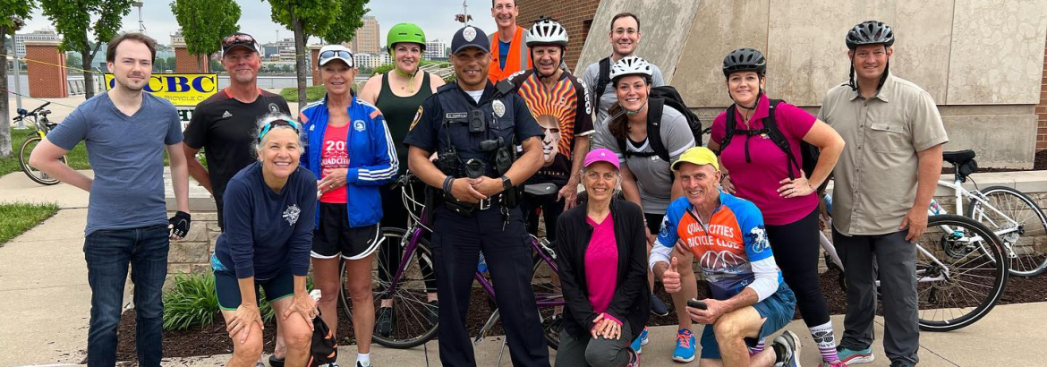 Men and women who ride bicycles standing next to police officer
